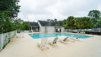 a swimming pool with chaise lounge chairs and a club house in the background